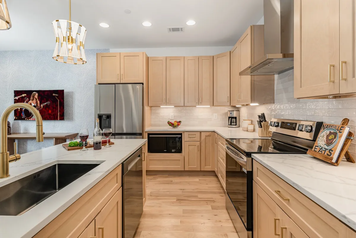 A bright, functional kitchen area centered around a large island with gold accents and modern appliances. The space is set up for both cooking and entertaining, with plenty of room for collaborative efforts and gatherings.